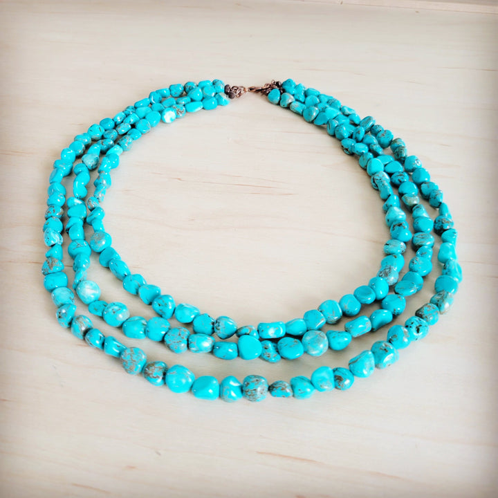 Triple-strand turquoise bead necklace with layered rows and central metal connector