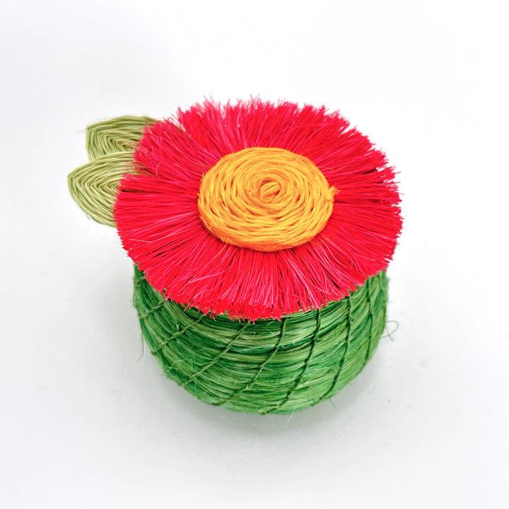 Tiny woven basket with green body and red flower lid with yellow center.