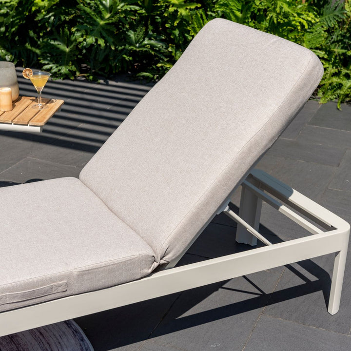 Light beige outdoor sun lounger with padded seat, adjustable backrest, and white frame