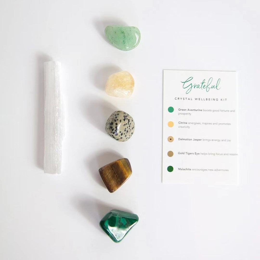 Crystal healing kit with white selenite wand, green and gold stones, and instructions card.