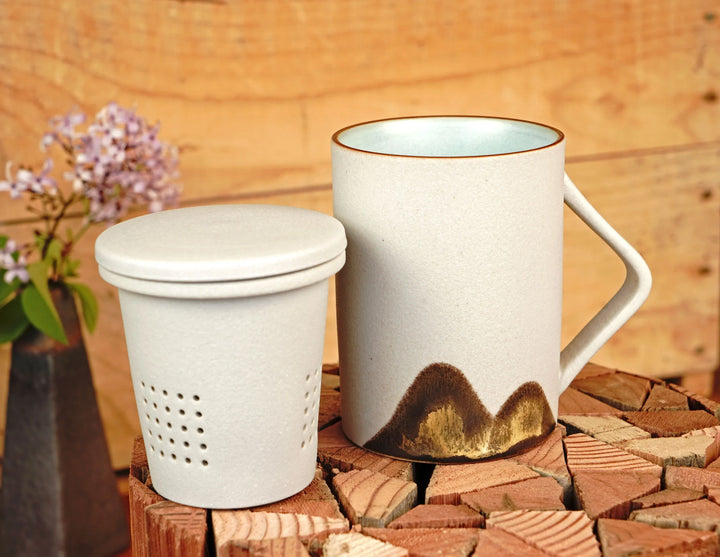 Ceramic tea mug with lid and built-in loose-leaf strainer, beige with dark mountain design