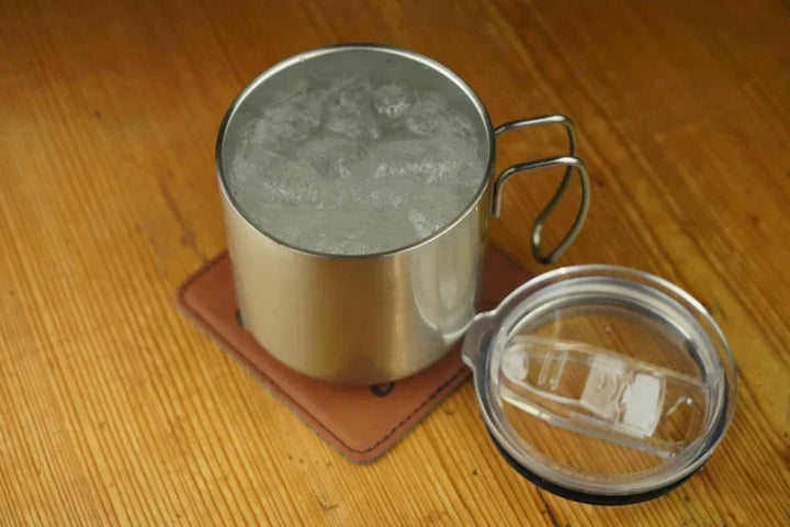 Stainless steel double-walled mug with lid on, condensation inside, loop handle.