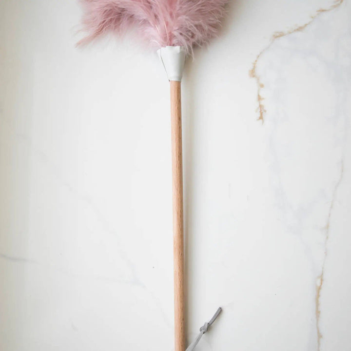 Wooden handle of pink ostrich feather duster with feather head and metal loop end
