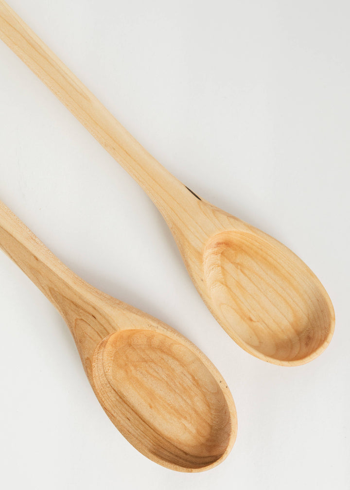 Two light wooden spoons with oval bowls and long handles, visible grain pattern