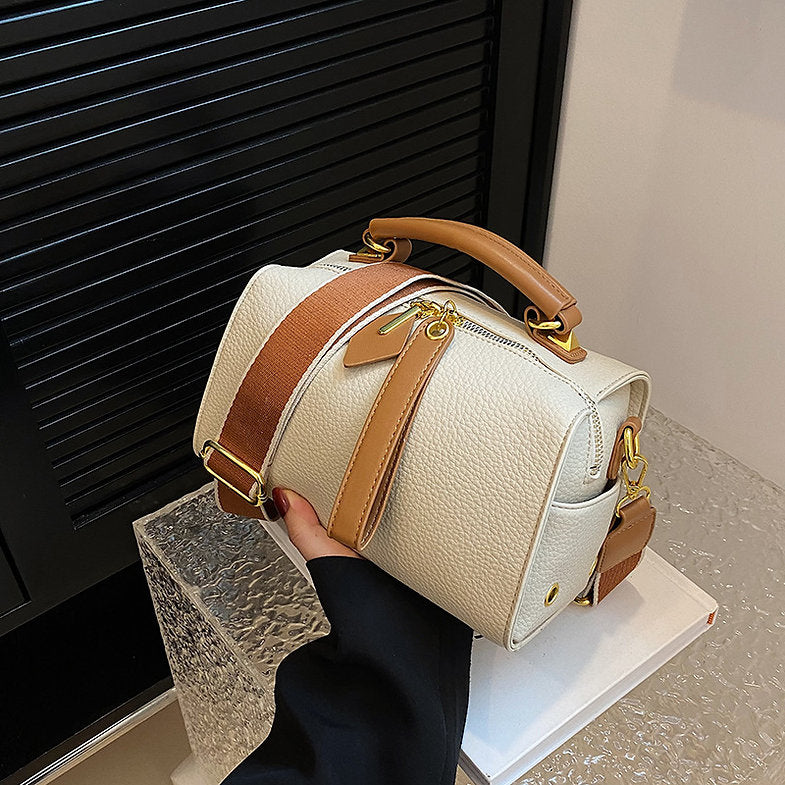White mini barrel bag with crossbody strap, gold-tone hardware, and front buckle