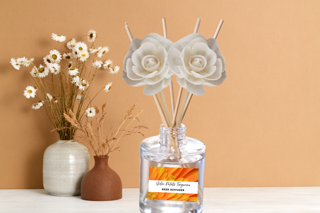 Clear reed diffuser bottle with white rose-shaped reeds on a tabletop