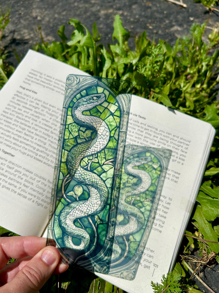 Green and teal serpent stained-glass bookmark on an open book page