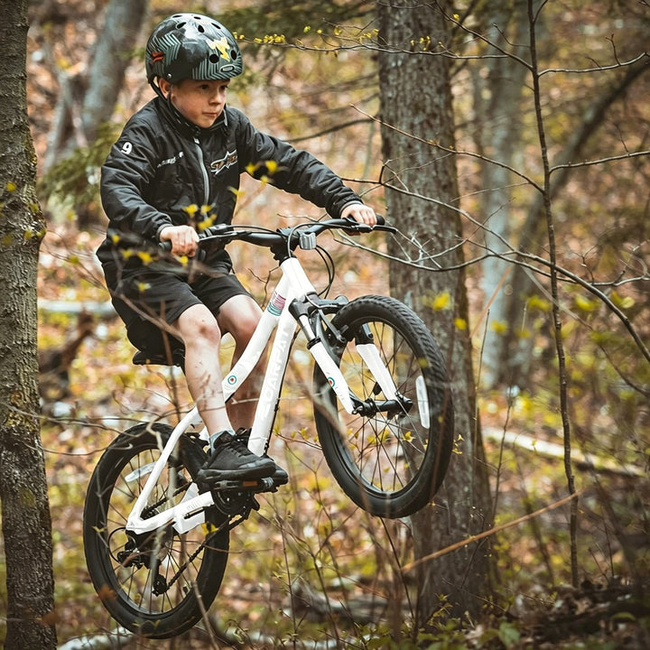 Kids mountain bike being ridden outdoors, white frame, front suspension, knobby tires