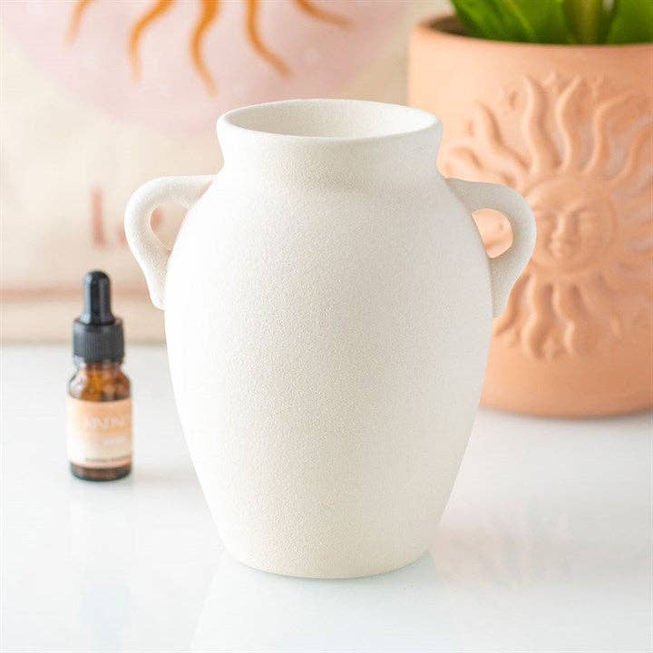 White vase-shaped wax warmer with curved side handles, no flame visible