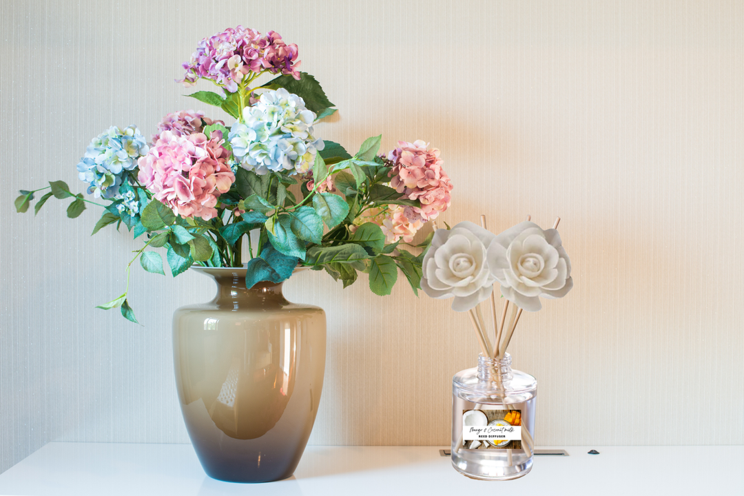 Clear glass reed diffuser with multiple rose-shaped reeds and labeled bottle