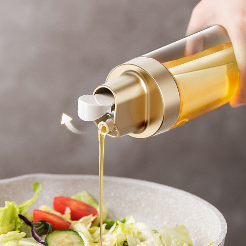 Clear glass oil dispenser with gold cap and spout pouring golden oil