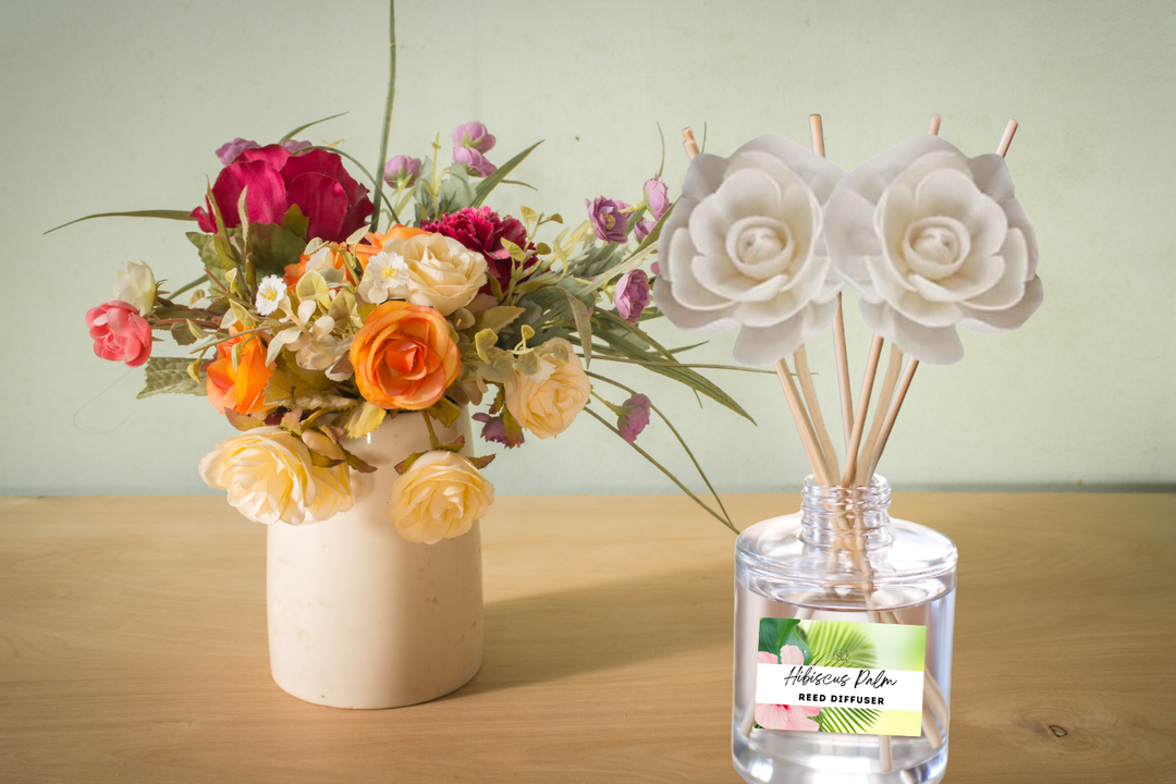 Reed diffuser bottle with wooden reeds on wooden surface, floral bouquet beside it