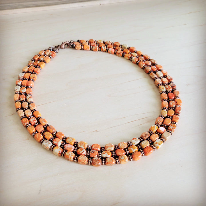 Beaded triple strand necklace with orange and cream segmented beads on bronze chain