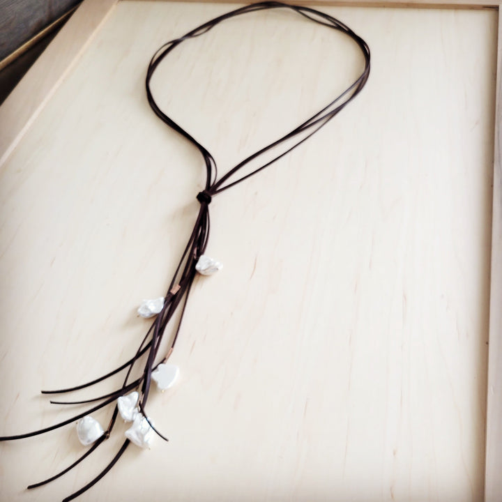 Dark brown leather cord necklace with knotted center and dangling white pearl beads