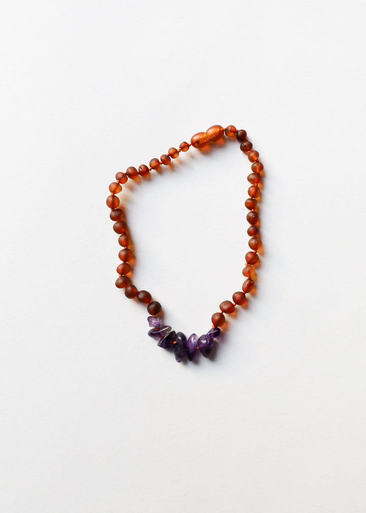 Raw amber beaded necklace with amethyst cluster at the bottom, flat lay