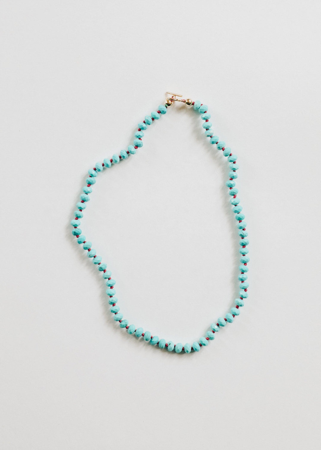 Turquoise beaded necklace with a small gold toggle clasp and round faceted beads.