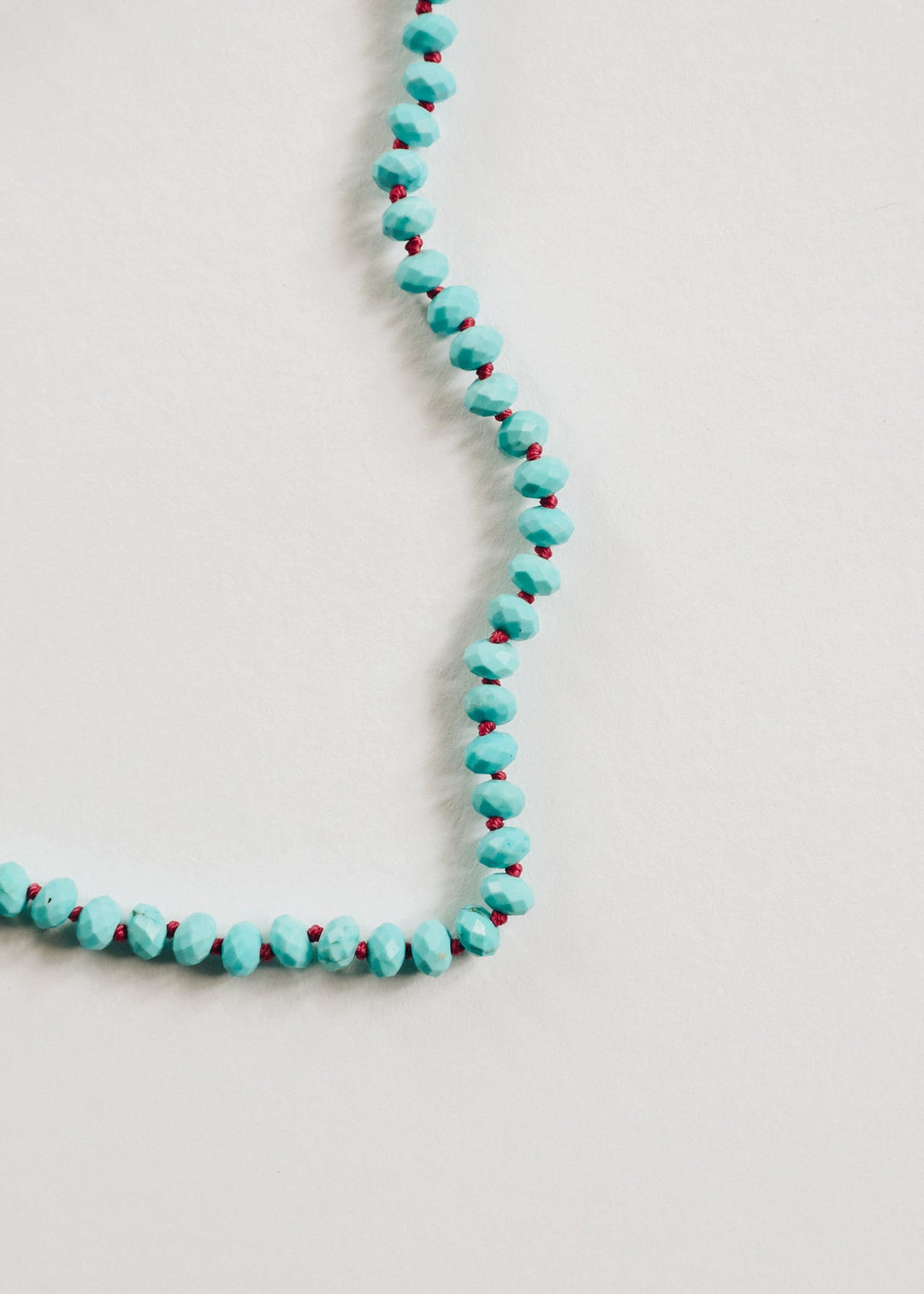 Turquoise beaded necklace featuring round, faceted beads on a flexible chain.