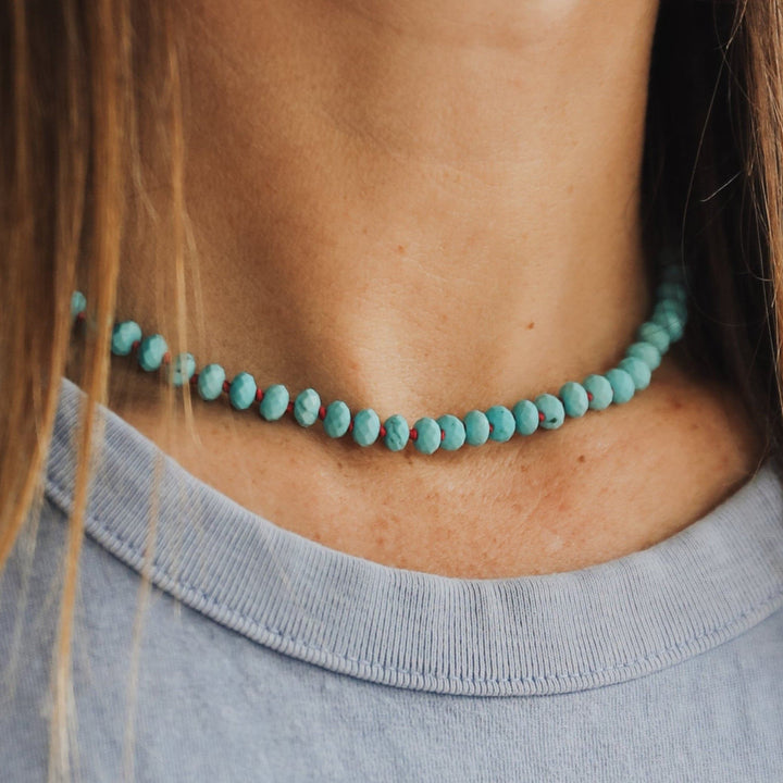 Turquoise beaded necklace with small gold toggle clasp; faceted round beads.