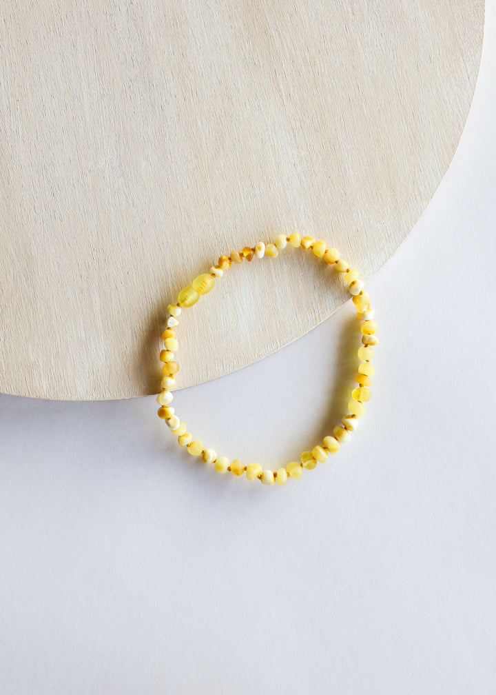 Yellow amber bead necklace displayed in a partial oval
