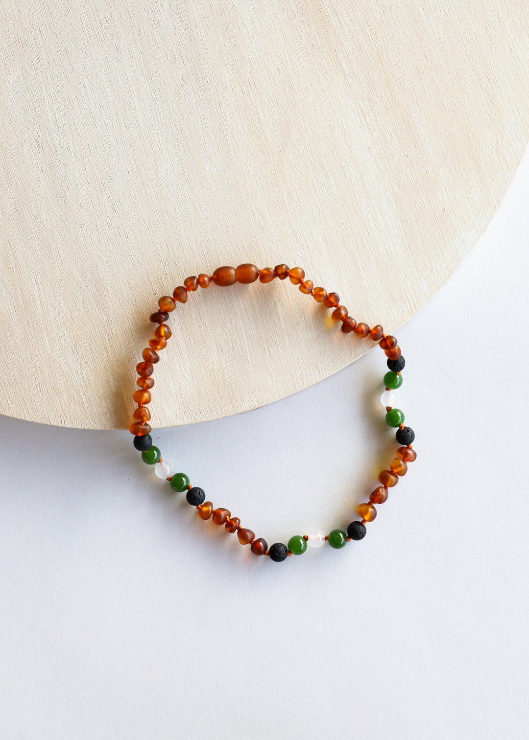 Amber bead necklace shown in open circle, with green and black bead accents