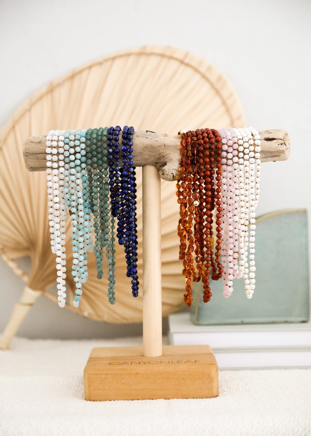 Stack of beaded bracelets with white pearl strands and blue-green and orange beads
