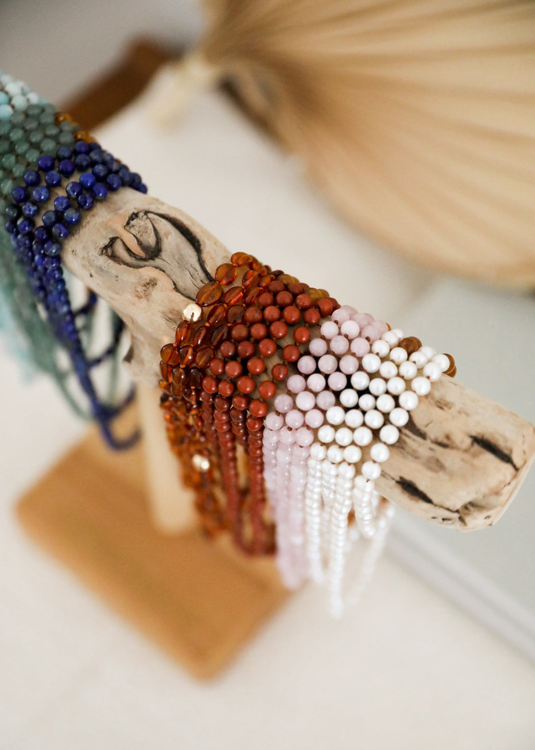 Close-up beaded bracelet with orange gemstone beads and white pearl fringe on tan cord