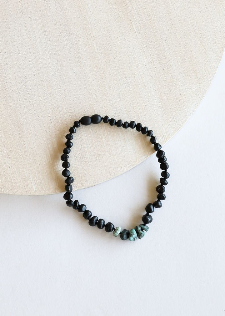 Black beaded necklace with small turquoise stone accents along the bottom edge