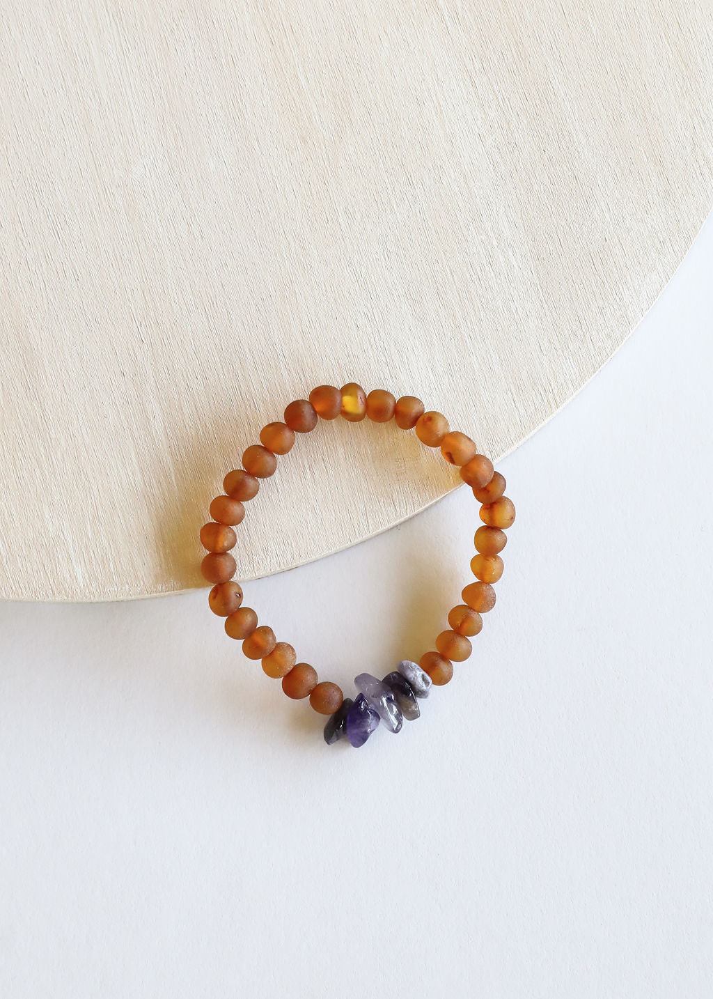 Amber-brown bead bracelet with small purple amethyst pieces on white