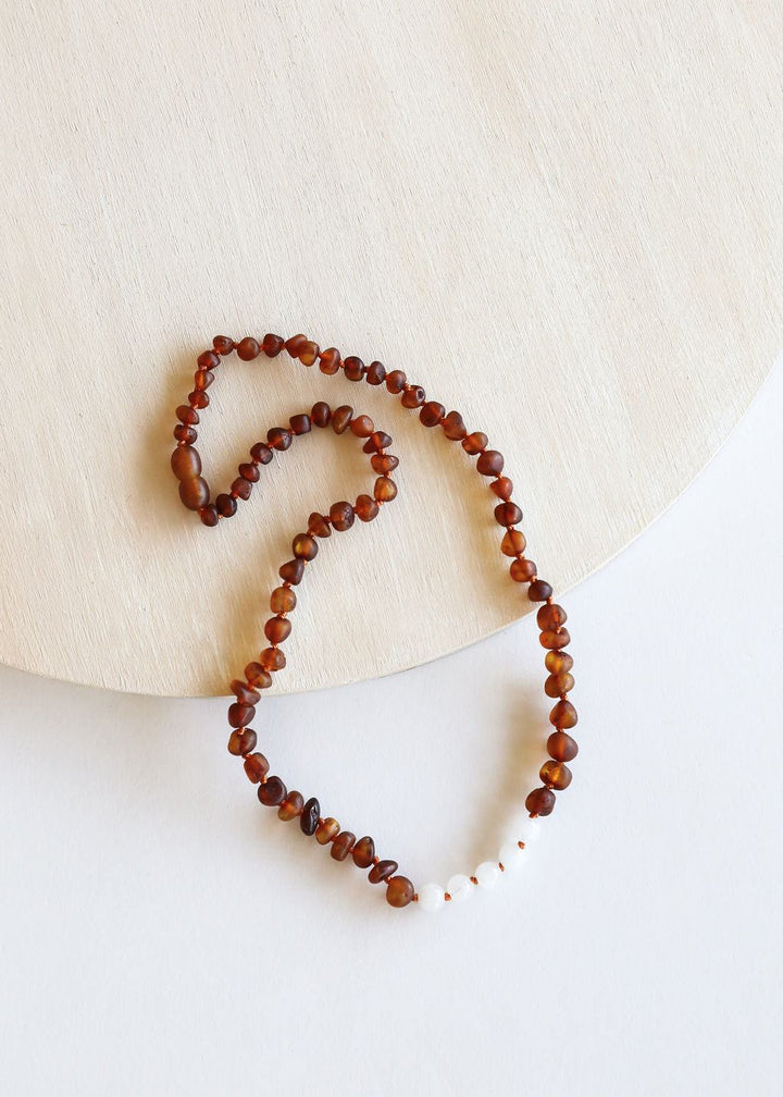 Raw amber beaded necklace laid out flat with white moonstone bead details
