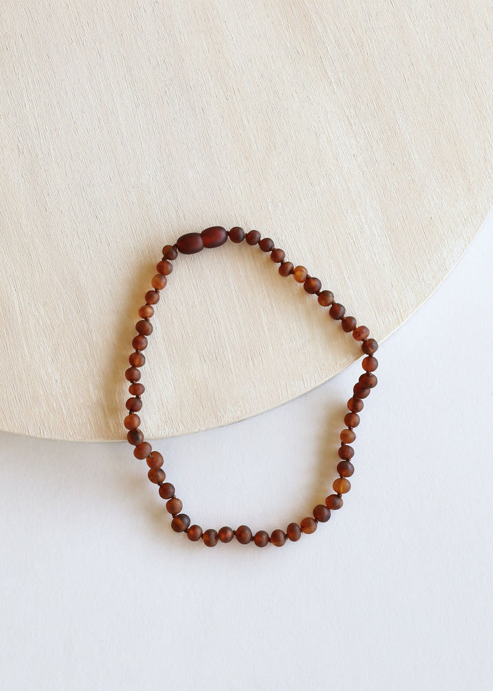 Round amber bead necklace, cognac and dark beads on a looped strand.
