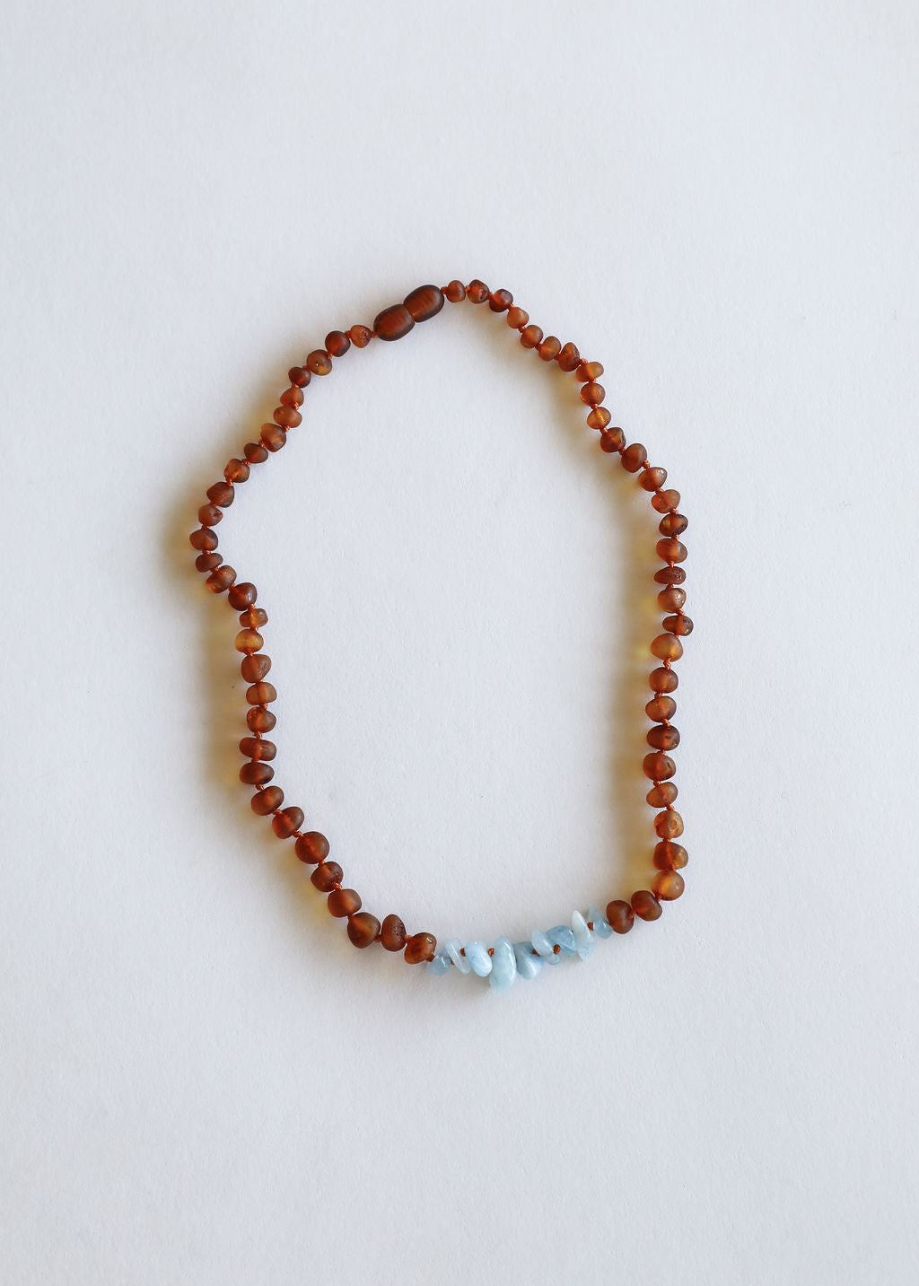 Amber brown beaded necklace with light blue stones at the bottom center
