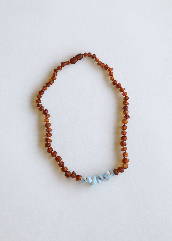 Amber brown beaded necklace with light blue stones at the bottom center