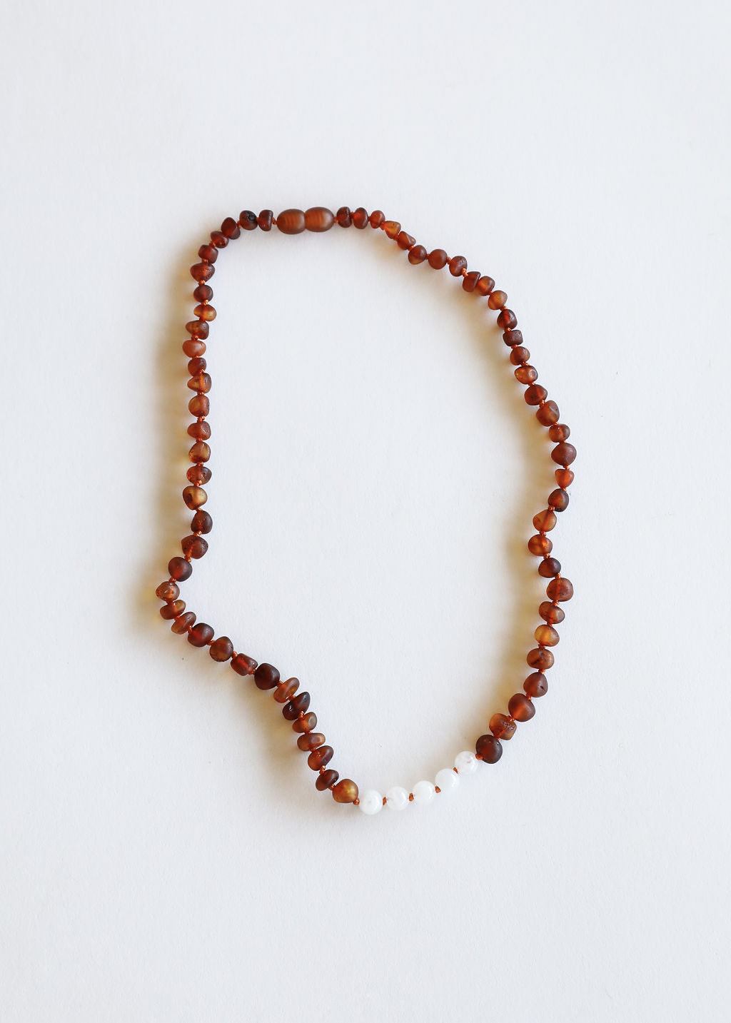Raw amber beaded necklace looped on a light background with white moonstone beads