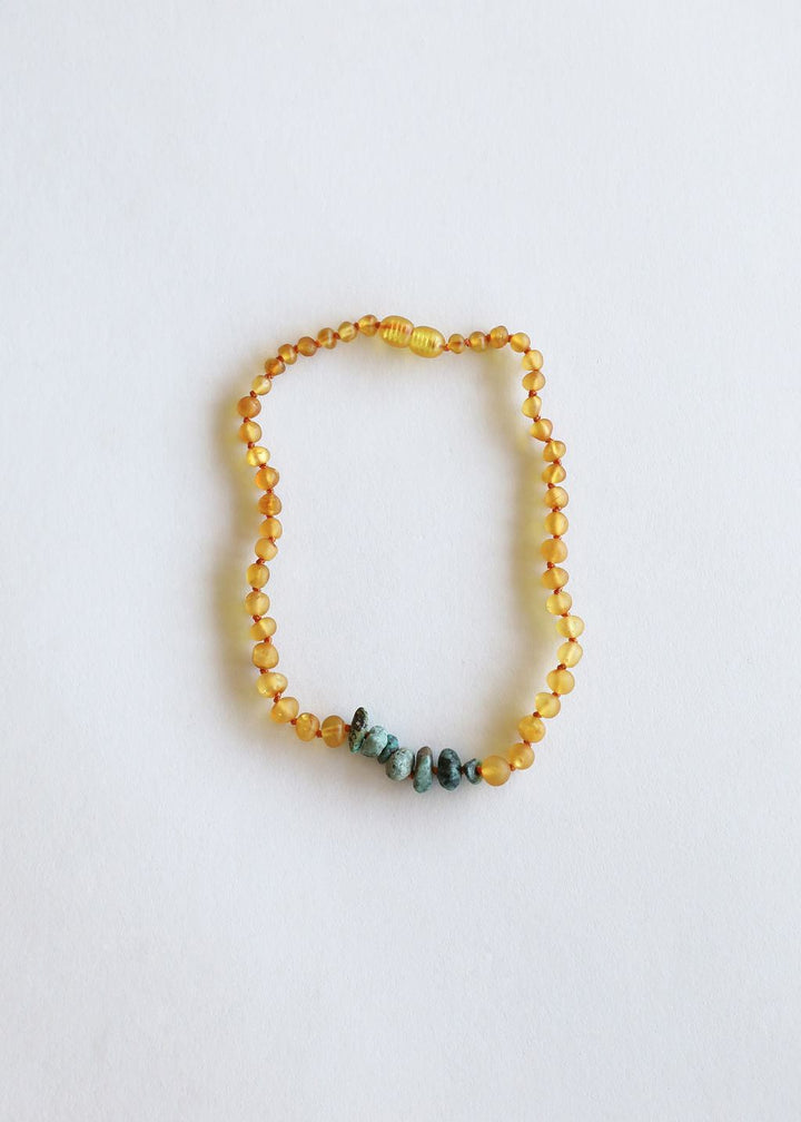 Amber bead necklace featuring turquoise rough stones along bottom edge.