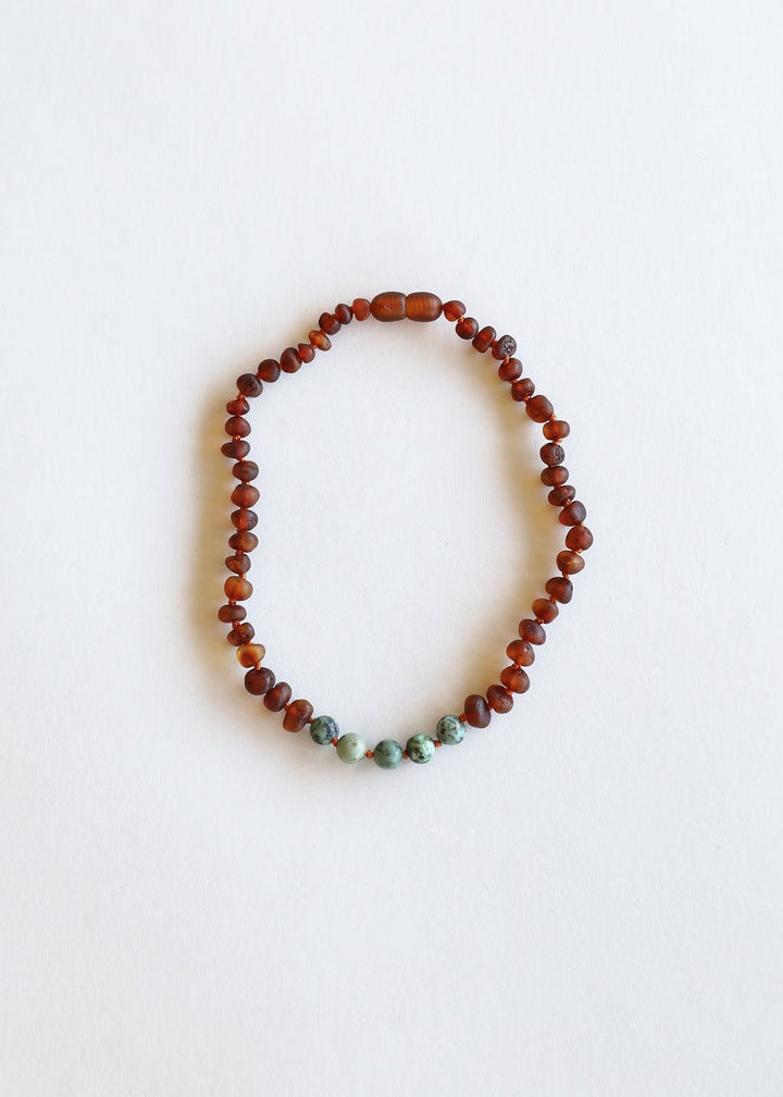 Beaded amber necklace with small teal stone accents along the bottom
