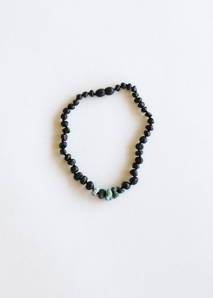 Black beaded necklace with turquoise stone beads at the center bottom