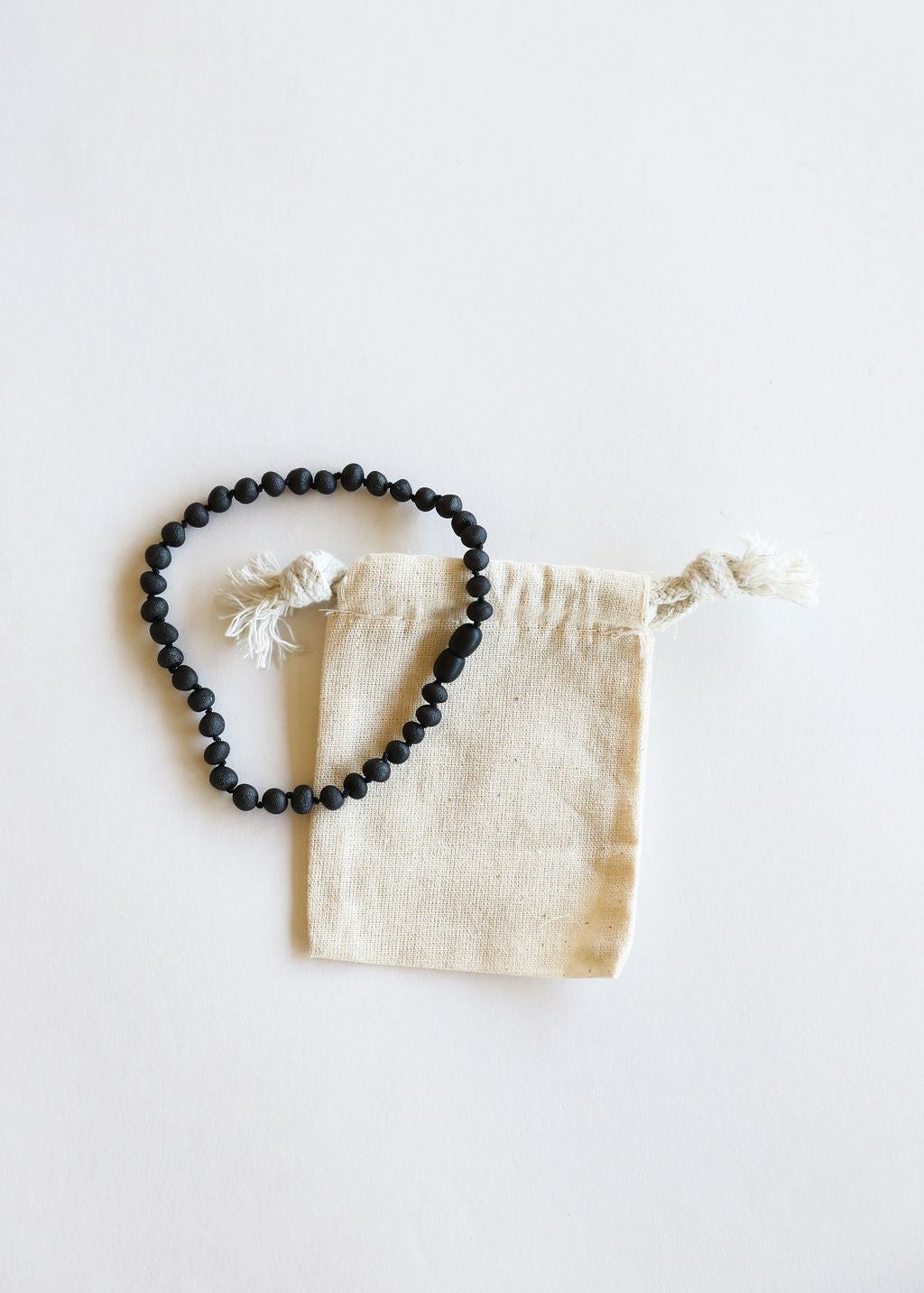 Black amber bead necklace laid with cream drawstring pouch