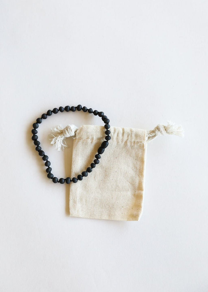 Black amber bead necklace laid with cream drawstring pouch