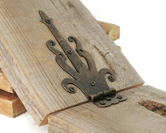 Bronze decorative strap hinge on wood, side angle with mounting holes visible