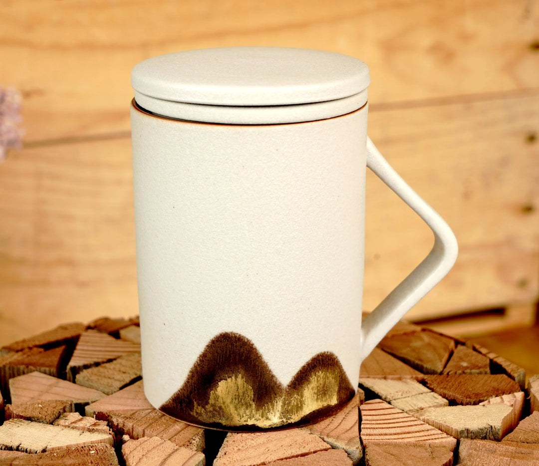Ceramic tea mug with lid and handle, beige with dark mountain pattern on lower front