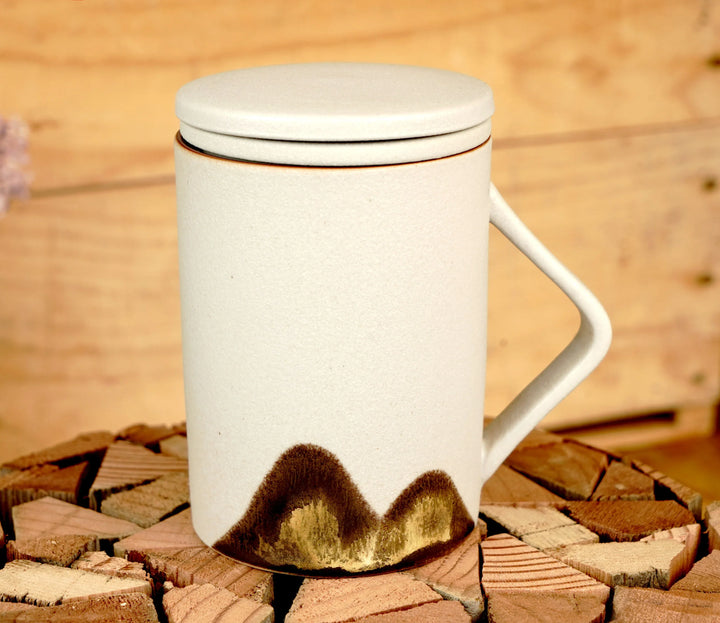 Ceramic tea mug with lid and handle, beige with dark mountain pattern on lower front