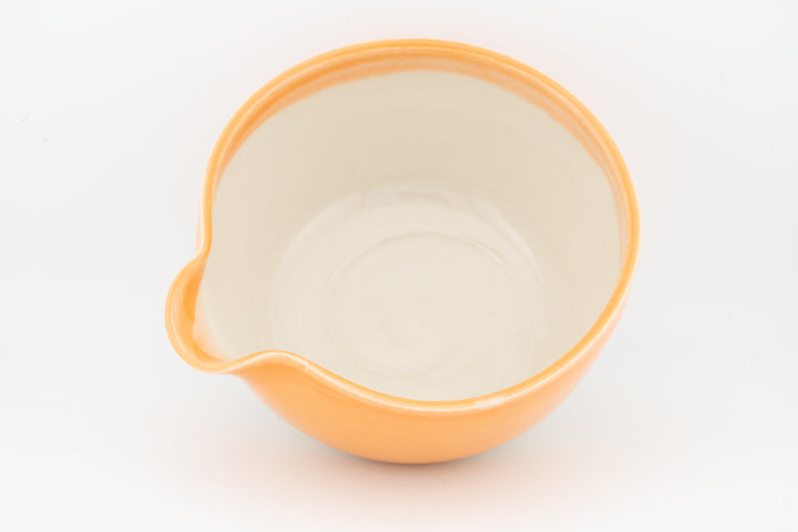Orange ceramic bowl with side spout, cream interior