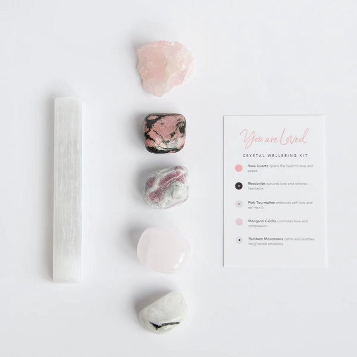 Crystal healing kit with white selenite wand, pink stones, and instructions card.
