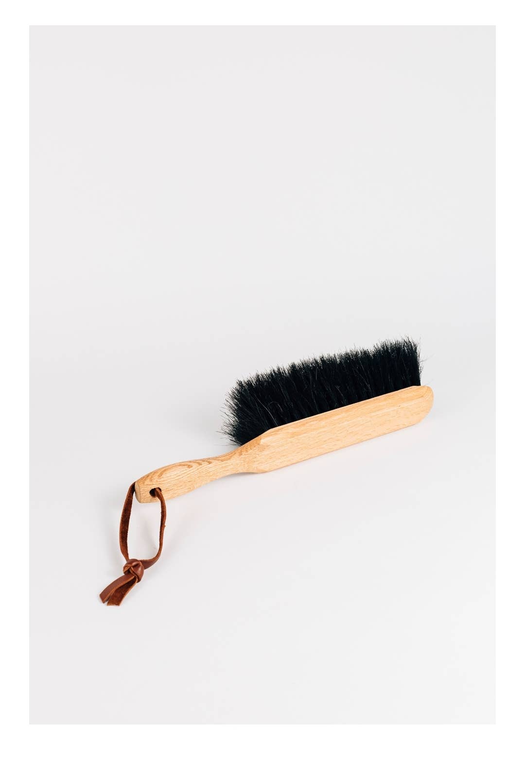 Horsehair dustbrush with wooden handle, dark bristles, and leather tie loop