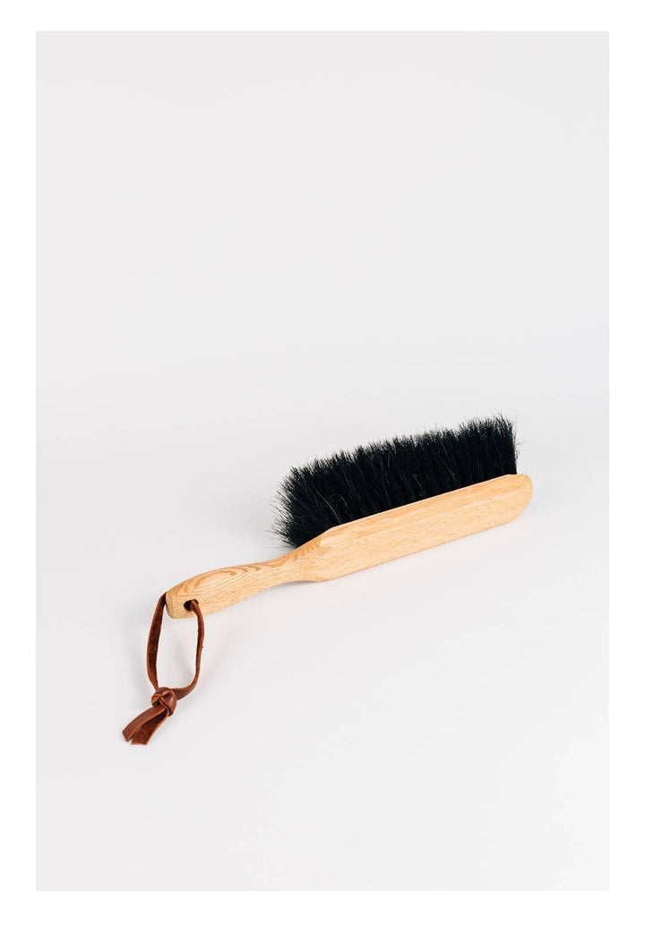 Horsehair dustbrush with wooden handle, dark bristles, and leather tie loop