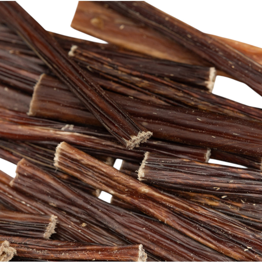 Beef gullet sticks close-up, dark brown dried strips with fibrous texture