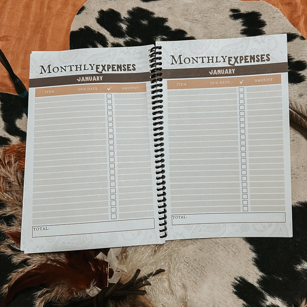 Open monthly expenses tracker notebook with January headings and lined table pages