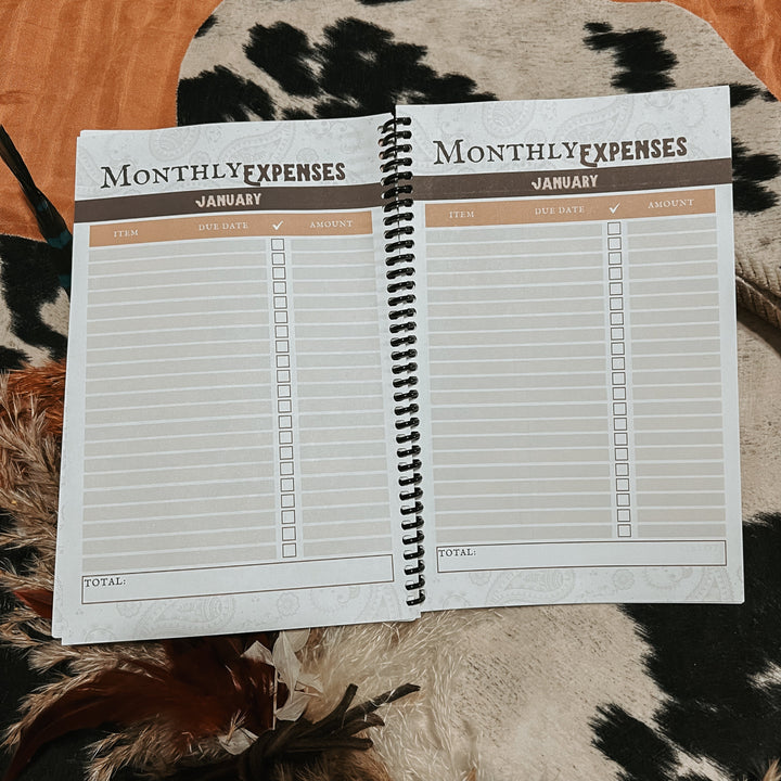 Open monthly expenses tracker notebook with January headings and lined table pages