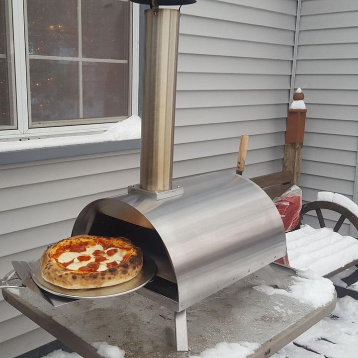 Stainless steel portable pizza oven with pizza on stone hearth outdoors