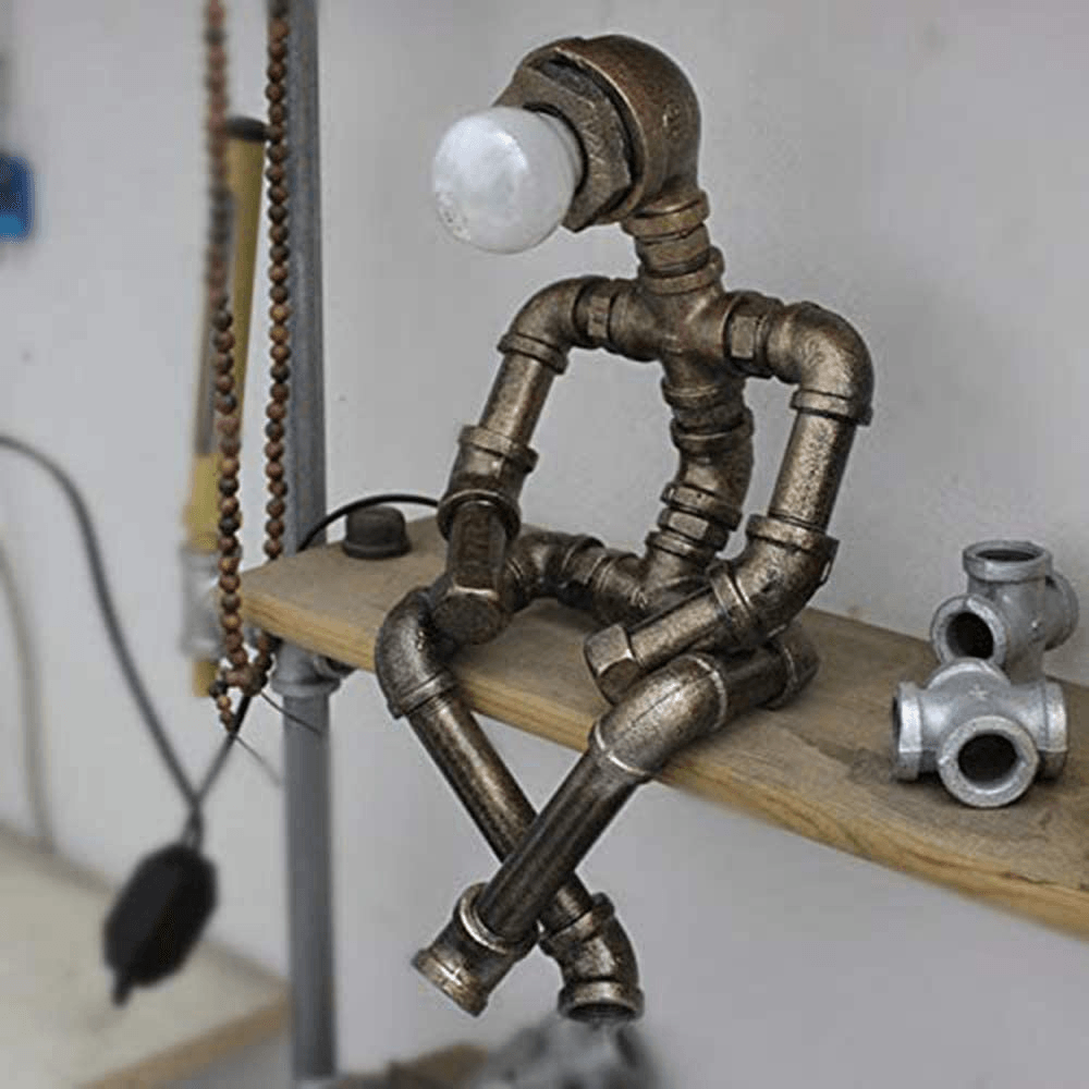 Dark metal steampunk table lamp with frosted bulb cap and pipe frame on wooden shelf